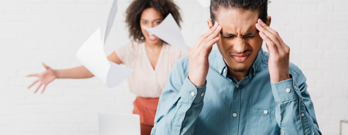 Businessman suffering from headache while his female colleague yelling in office