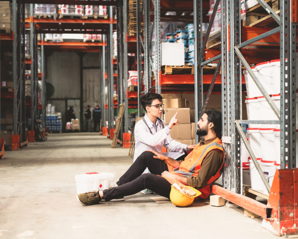 young-female-giving-first-aid-to-one-of-warehouse-workers